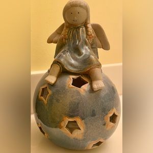 Ceramic Angel sitting on a globe of star cutouts that is a candle holder